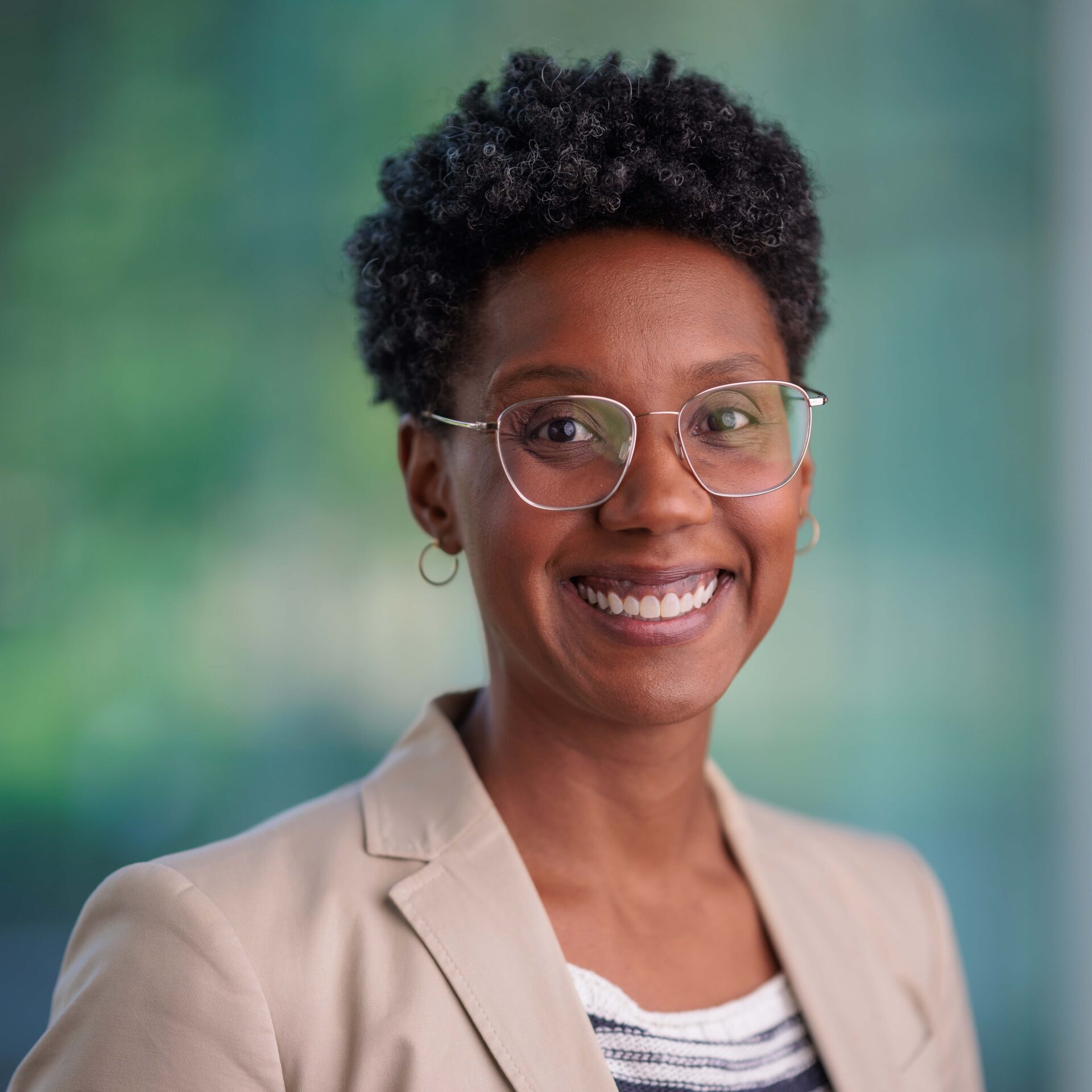 Headshot of a Black woman, wearing glasses and beige blazer.